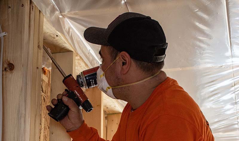 Installer insulating home's walls with blown-in insulation