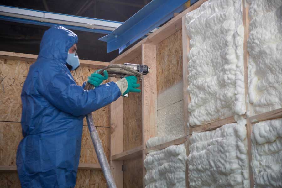 Spray foam insulation installer, insulating home's wall.