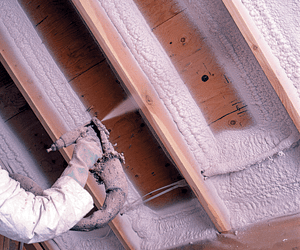 Worker installing spray foam insulation on a ceiling.