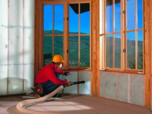 Installer insulating home's walls with blown-in insulation