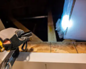 Attic insulation Services Shining a held held fashlight into an attic