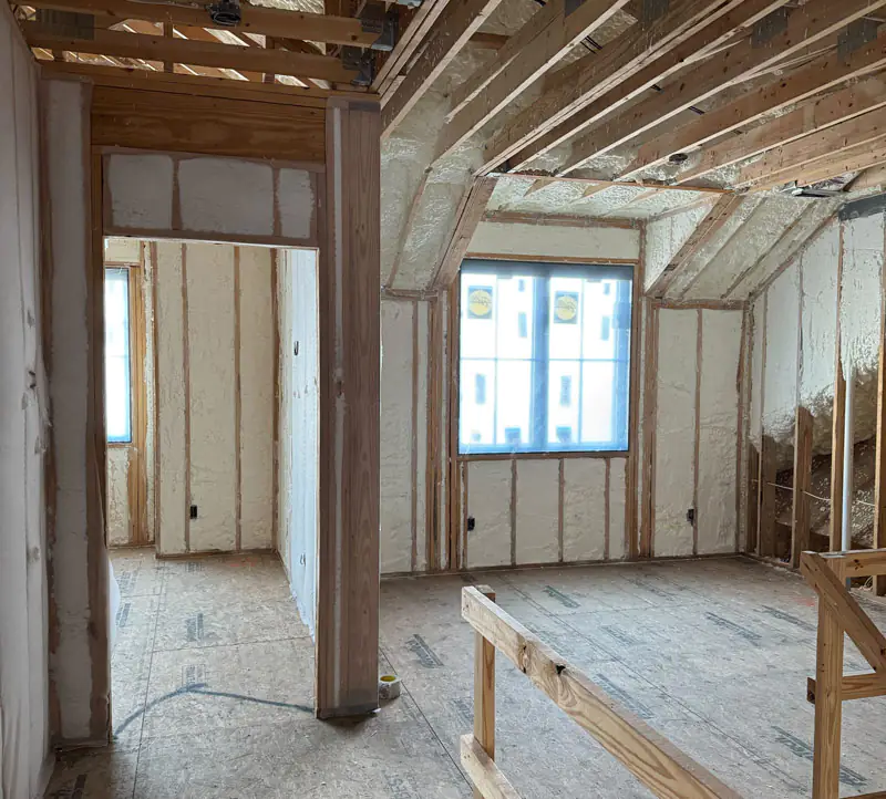 Spray foam insulation in progress within a framed residential interior, enhancing thermal protection and air sealing